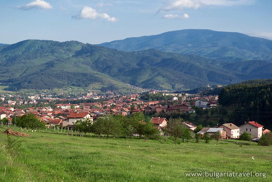 Scenic village nestled in mountains with lush green field and quaint houses.