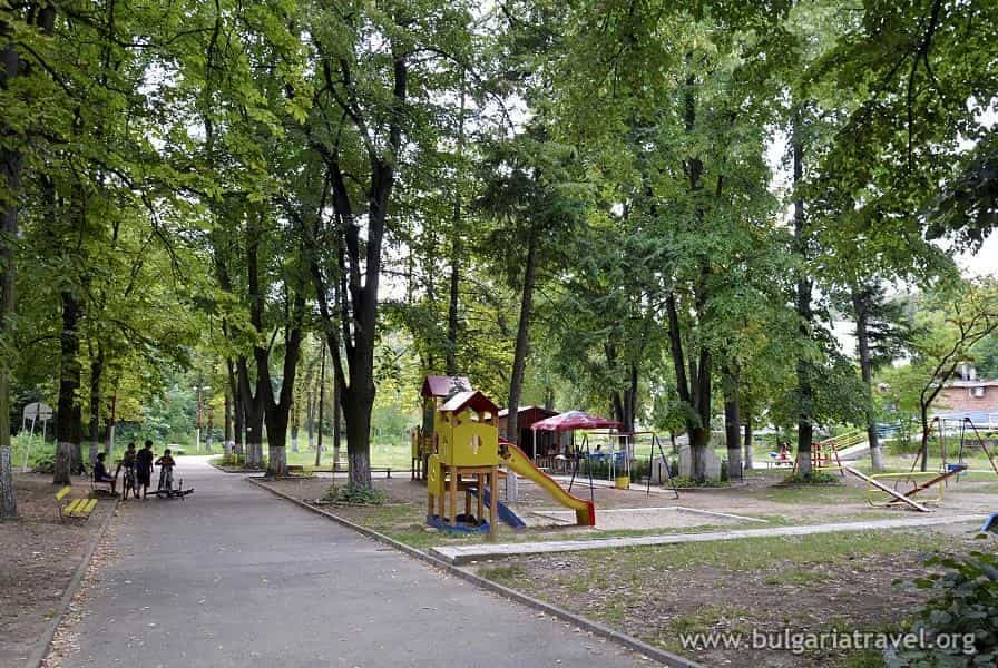 A park with a playground equipment and lush trees in the background.