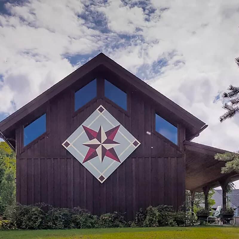 Unique rustic barn with quilt-inspired star design, set among lush greenery in Hardy County, West Virginia.