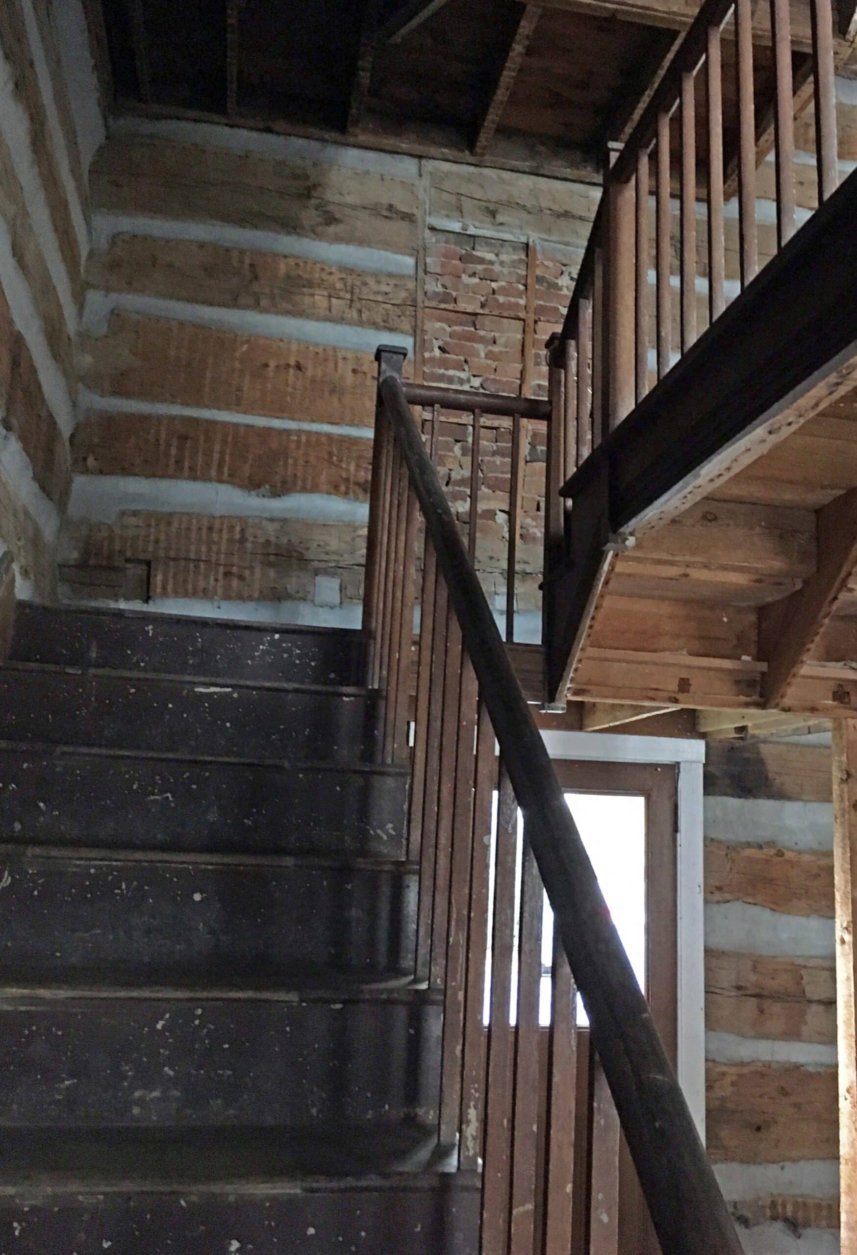 Rough-hewn wood and brick interior of a rustic mountain home staircase in Hardy County WV.