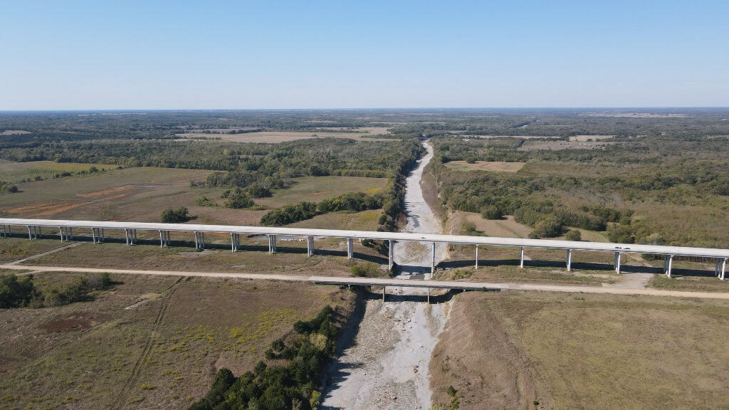 Aerial view of Ladonia landscape with a bridge crossing a dry riverbed.