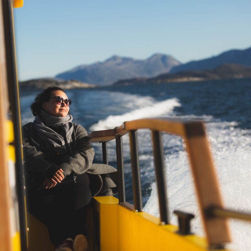 Woman relaxing on yellow boat during sunset. Photo - Magnus Biilmann Trolle, Visit Nuuk