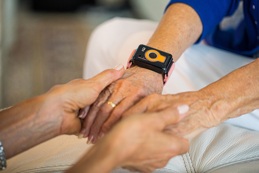 Wrist-worn emergency medical alert device on senior resident's wrist, highlighting senior safety and emergency response services at Vista Prairie at Garnette Gardens in Redwood Falls.