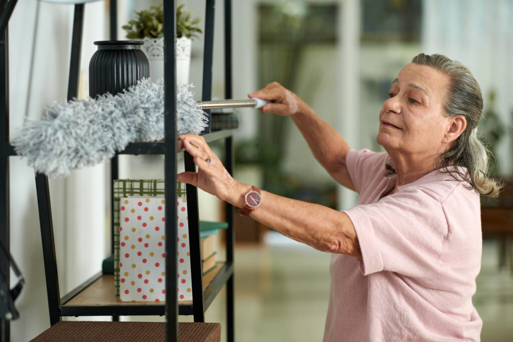 Senior woman cleaning a shelf at Vista Prairie at Garnette Gardens assisted living facility, showcasing senior-friendly living environment and engaging activities for residents in Redwood Falls, MN.
