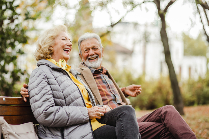 Senior living community at Vista Prairie Garnette Gardens in Redwood Falls, MN, showcasing happy residents enjoying outdoor park benches in a serene, natural setting.