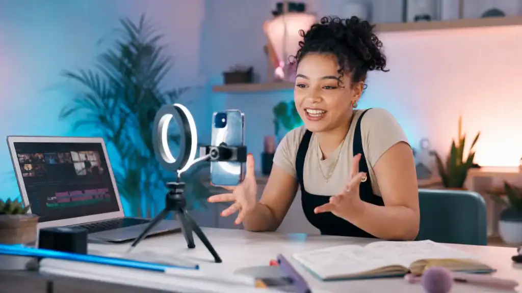 Young content creator apprentice filming short-form video with a ring light and editing on a laptop