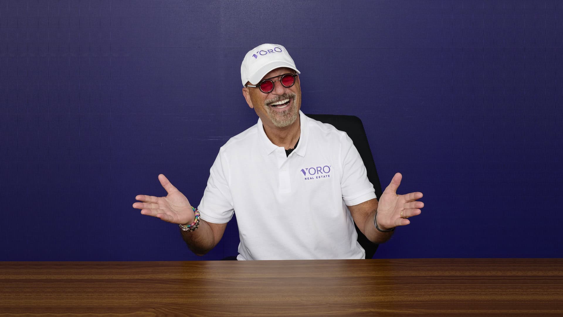 Smiling Voro team member wearing white polo and cap with logo, gesturing happily.