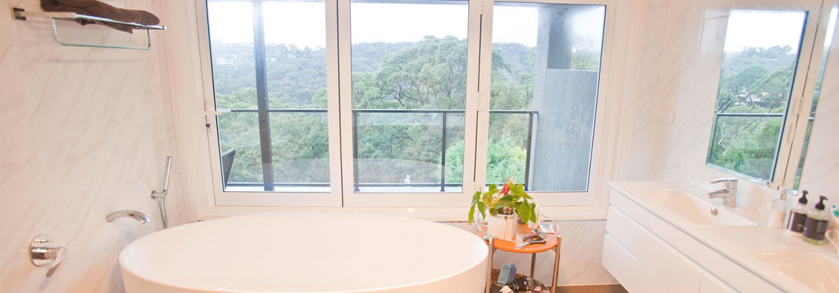 Bright bathroom featuring a white freestanding bathtub and expansive windows with scenic views.