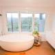 Bright bathroom featuring a white freestanding bathtub and expansive windows with scenic views.
