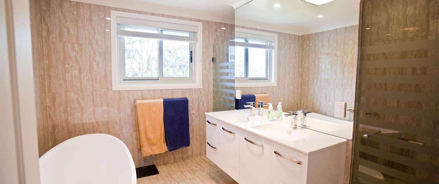 Bright bathroom featuring a bathtub, double vanity, and large windows in a Sydney residential projec.