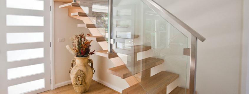 Staircase with glass balustrade and wooden steps inside a contemporary Sydney residence.