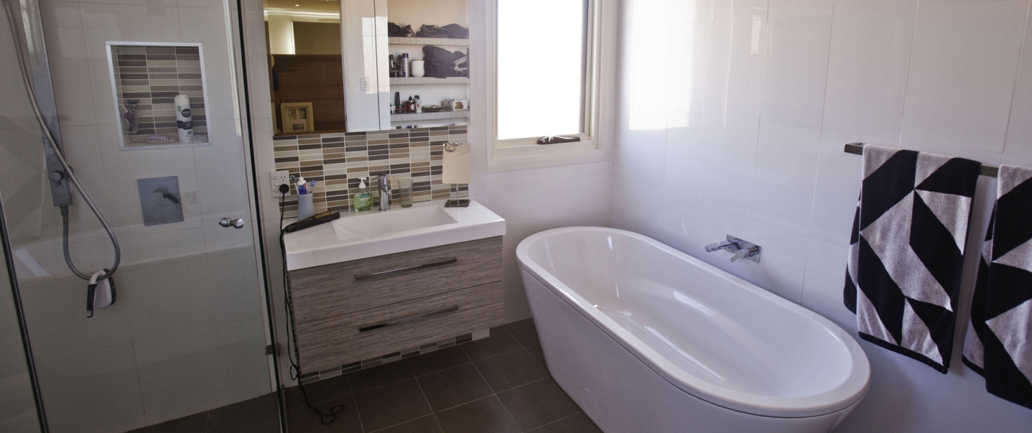 Contemporary bathroom featuring a white bathtub, modern vanity, and decorative tiles in a Sydney hom.
