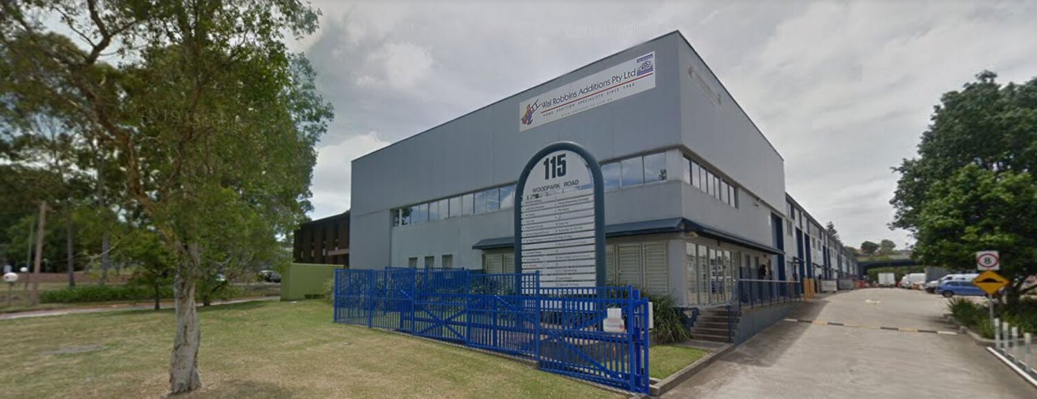 Commercial building with blue fencing and landscaped surroundings in Sydney.