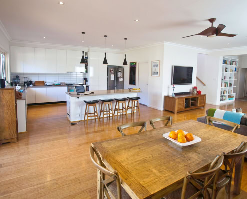 Bright and modern kitchen with island bench and seating, adjacent to a cozy dining space with wooden.
