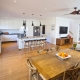 Bright and modern kitchen with island bench and seating, adjacent to a cozy dining space with wooden.