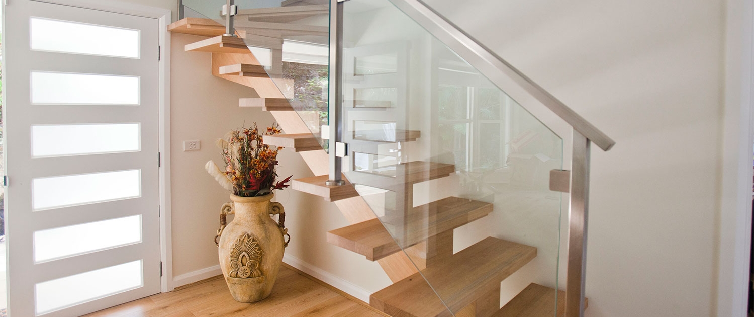 Modern interior staircase with wooden steps and glass panels in a residential home.