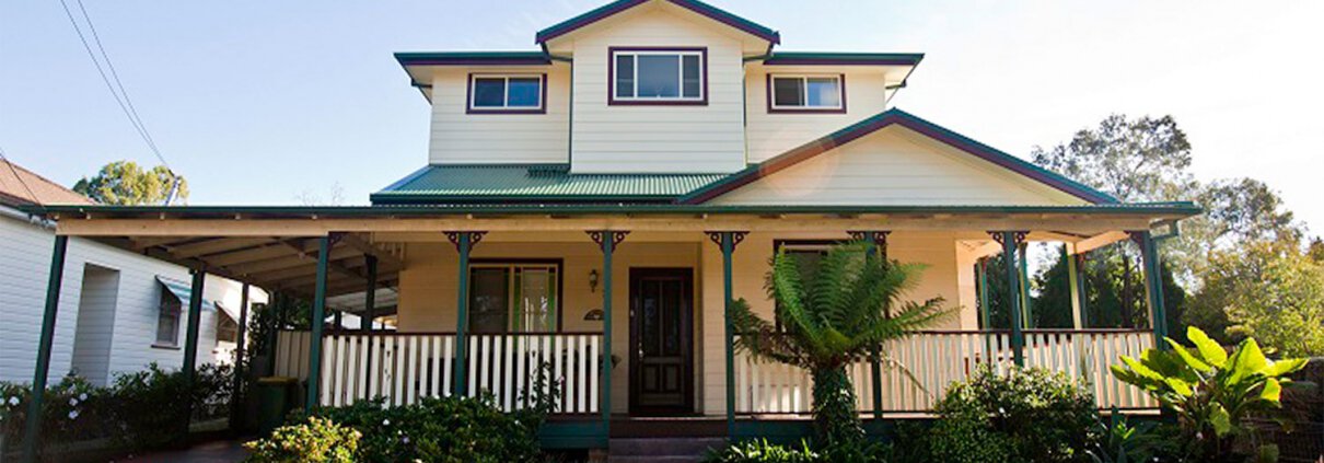 Beautiful two-story Sydney home with a spacious front porch and lush garden.