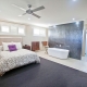 Interior of a contemporary bedroom featuring a freestanding bathtub, black accent wall, and ample na.