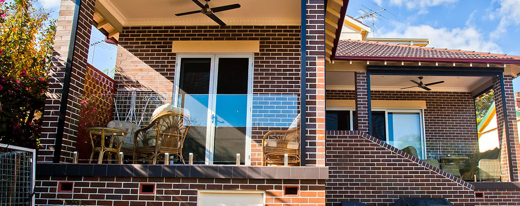 Outdoor balcony with brick walls, ceiling fan, and patio furniture in a Sydney home.