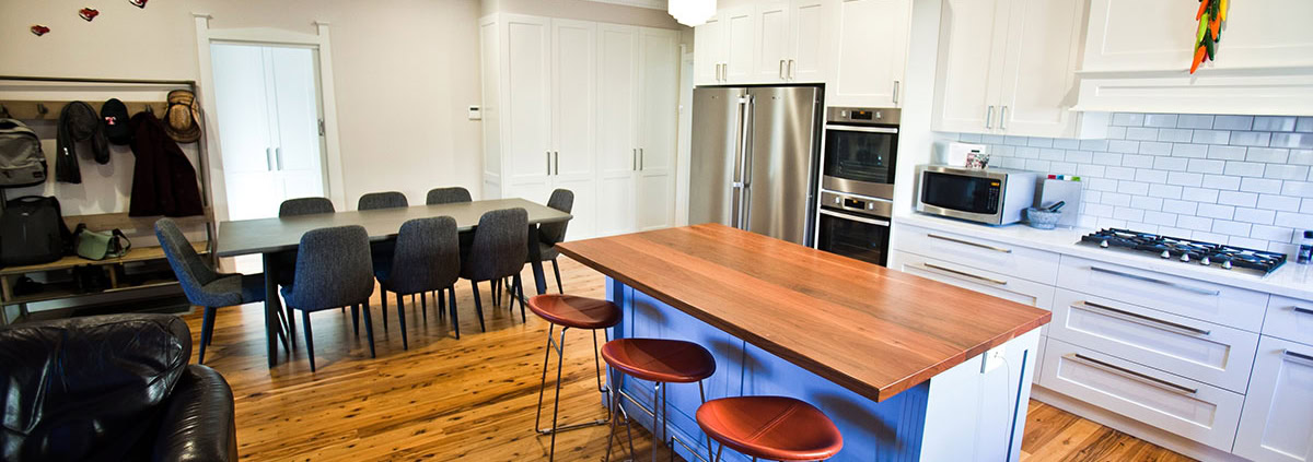 Spacious kitchen featuring a central island, white cabinetry, and a dining table with eight chairs i.