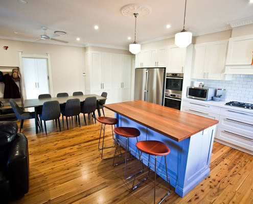 Spacious kitchen featuring a central island, white cabinetry, and a dining table with eight chairs i.