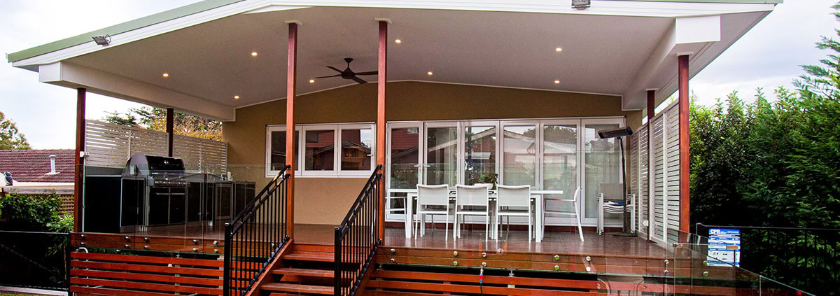 Covered outdoor deck with dining space and BBQ in a Sydney backyard.