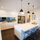 Bright, contemporary kitchen with white cabinetry, island, and black pendant lights in Sydney home.