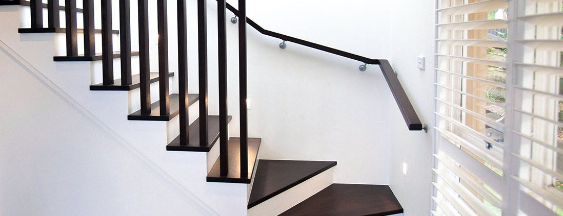 Interior staircase with dark wood steps and black metal handrail in a residential home.