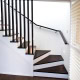 Interior staircase with dark wood steps and black metal handrail in a residential home.