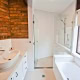 Bright bathroom with brick wall, white fixtures, and a large window in a Sydney home renovation.