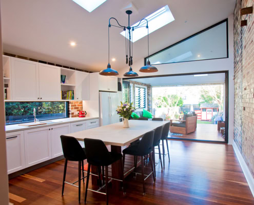 Bright, airy interior featuring white cabinetry, wooden flooring, and contemporary lighting fixtures.