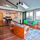 Spacious living room with brick walls, wooden floors, and large louvered windows in a Sydney home.