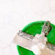 Tiling tools including a trowel and grout on a green bucket in a bathroom.