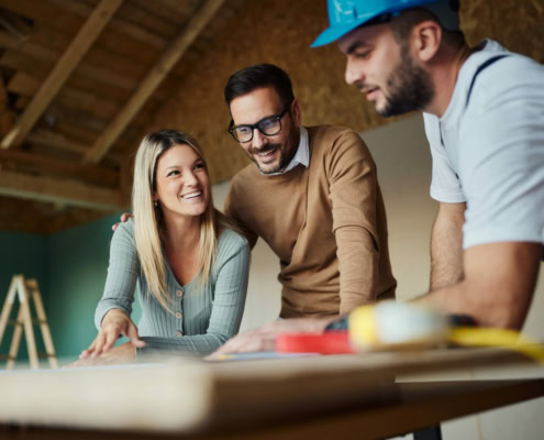Two men and a woman discussing home renovation plans inside a new residential building.
