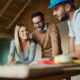 Two men and a woman discussing home renovation plans inside a new residential building.