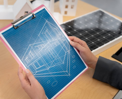 Blueprint of a house on a clipboard with architectural drawings.
