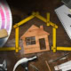 House model with measuring tape, tools, and design materials for home renovation.