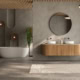Contemporary bathroom featuring a bathtub, wooden vanity, round mirror, and minimalist decor.