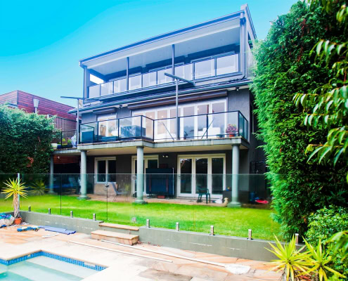 Sydney residential home extension with glass balconies and outdoor living space.