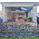 Outdoor living area with brick walls, wooden steps, and contemporary furniture in a residential back.