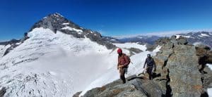 Climbers ascending Mount Aspiring with snow and rocky terrain in the background.