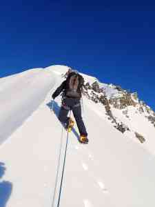 Climber ascending Mount Dixon's snowy slope with clear blue sky background.