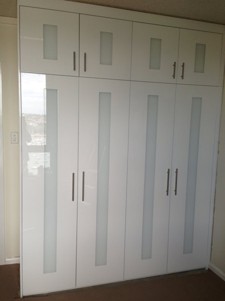 Modern white wardrobe with glass panel doors in Sydney home.