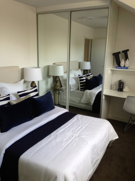 Modern bedroom featuring a built-in wardrobe, white bedding, and navy accents in Sydney.