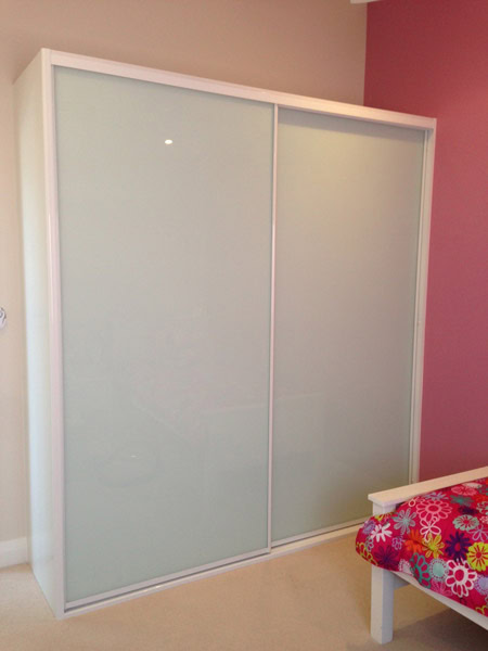White sliding wardrobe with frosted glass doors for bedroom organisation.
