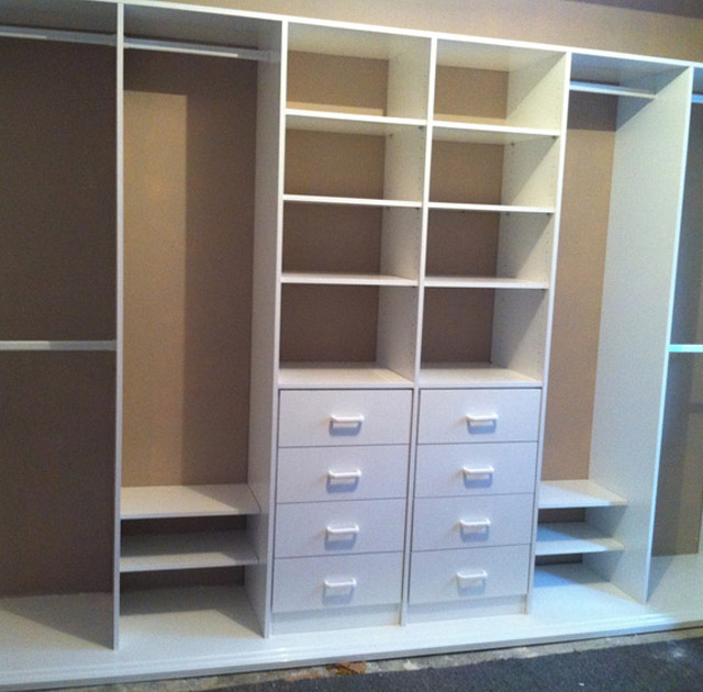 Custom built wardrobe with multiple shelves and drawers in white finish.