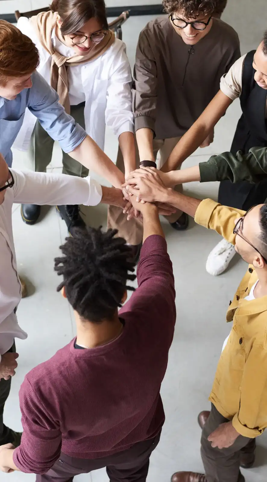 Diverse team huddling in unity, hands joined together.