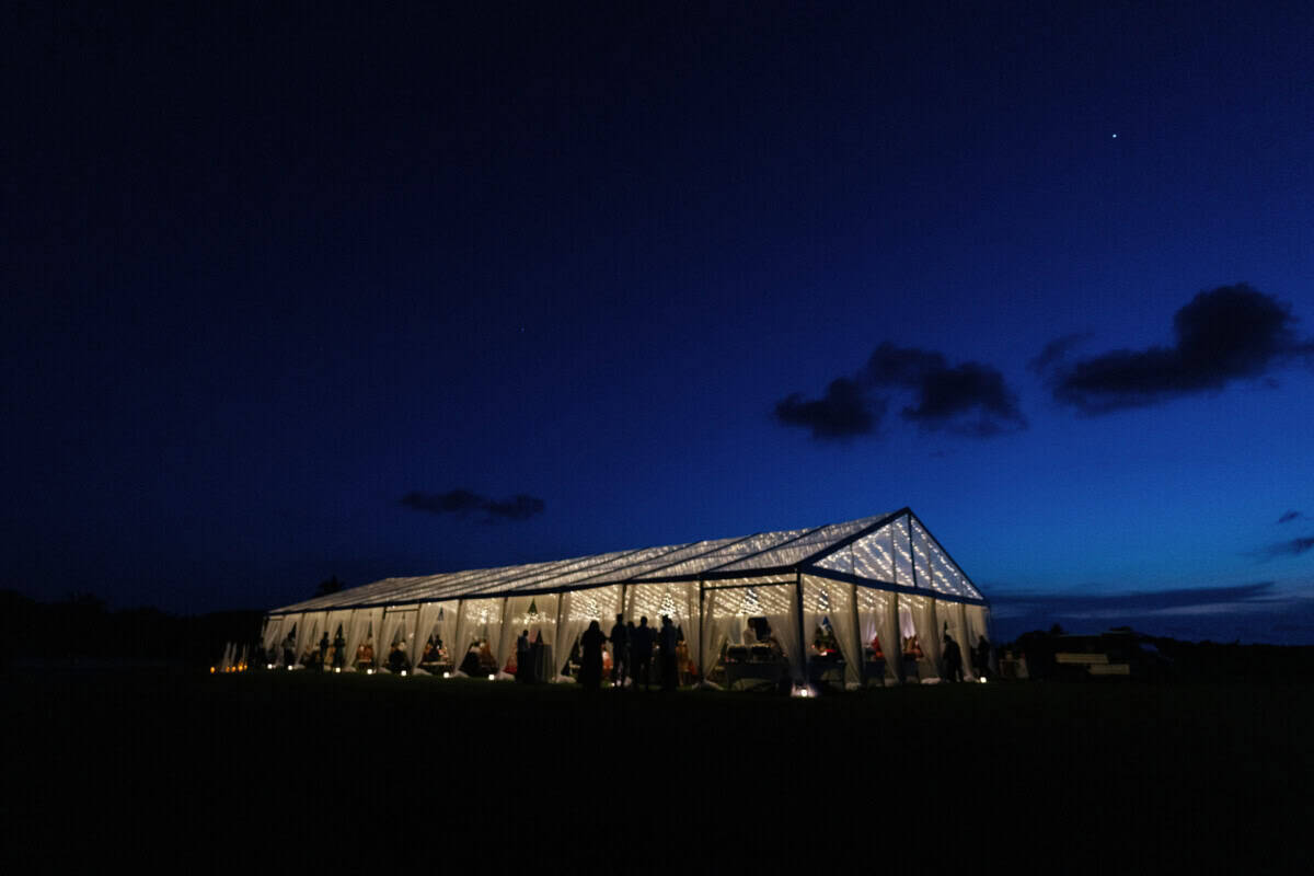 Beautiful nighttime outdoor wedding reception under a luminous tent with string lights, ideal for luxury wedding planner services.