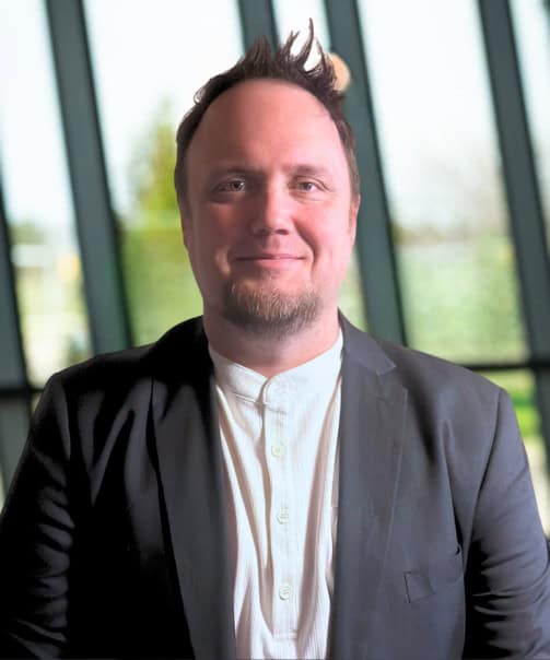 Portrait of Billy D Mann, West Michigan Ironmen team leader, smiling indoors.