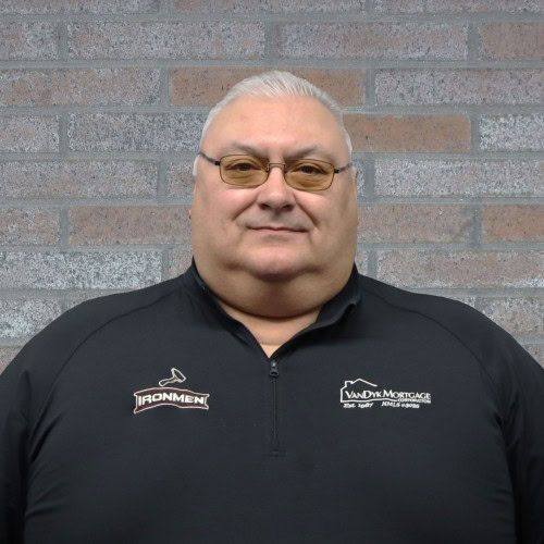 West Michigan Ironmen team owner standing against brick wall.